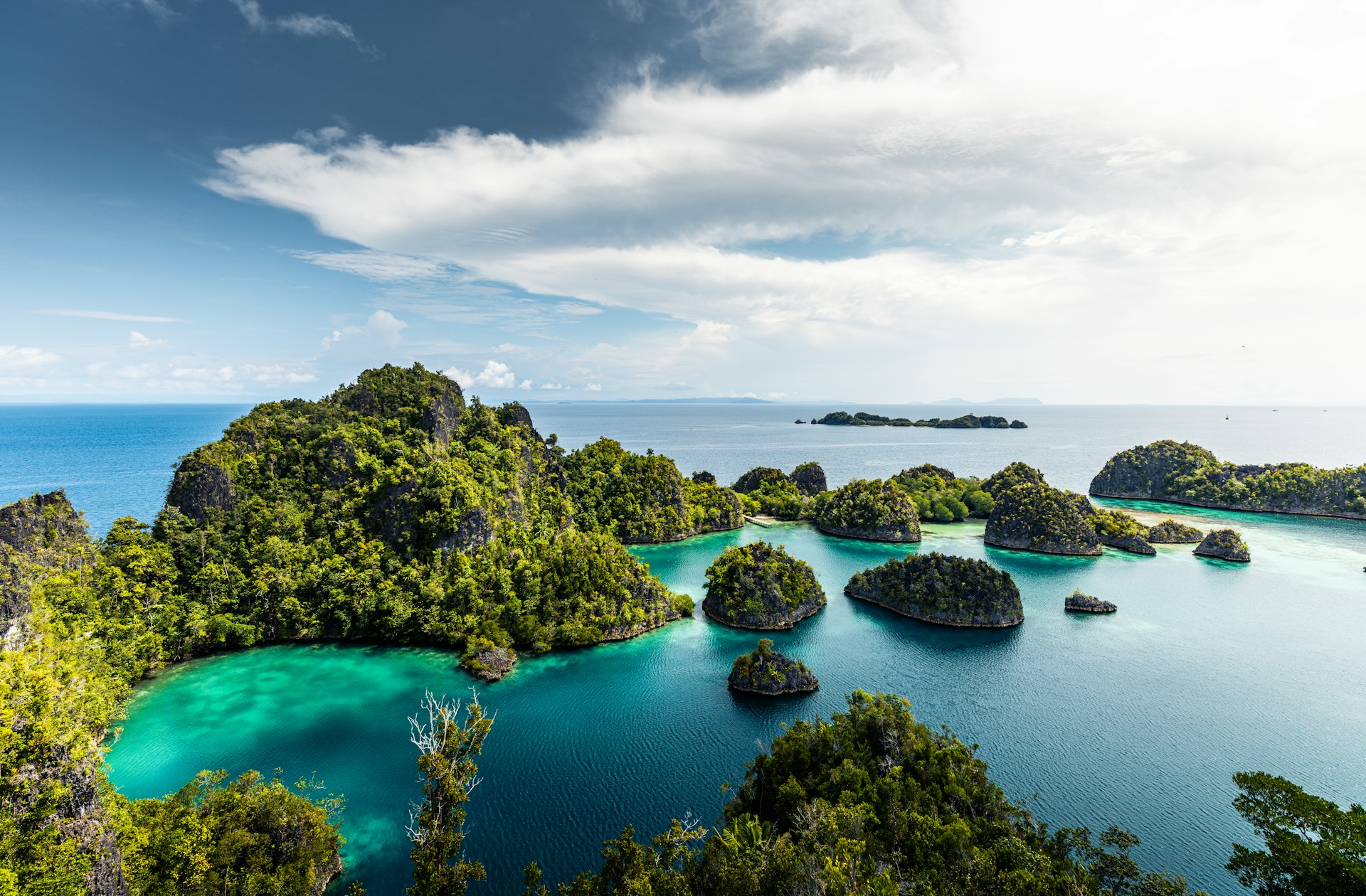 Gugusan pulau karst hijau di atas laut biru tenang di Raja Ampat, Papua Barat.