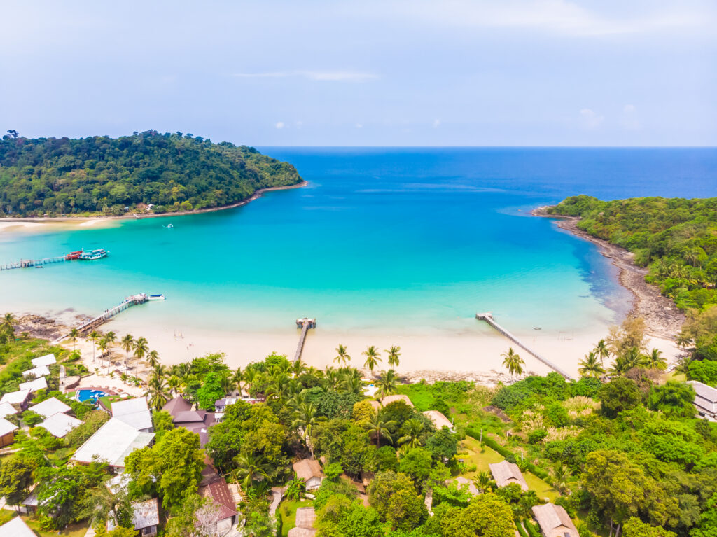 Pemandangan pantai tropis dengan air laut biru jernih dan hutan hijau di Kepulauan Riau.