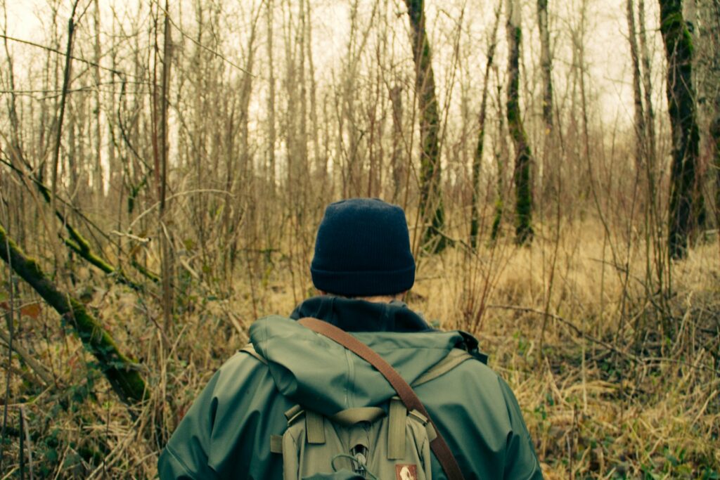 A survivalist stops and observes the forest environment while applying the STOP survival method.